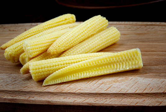Young corn on a wooden cutting board . Delicious baby corn.