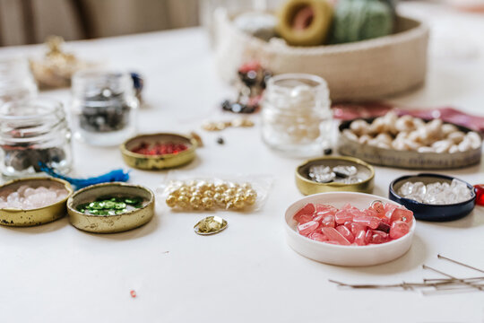 Side view of various decorative bugle beads in metal containers on wooden table