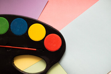 multicolored paints on with brushes on cardboard