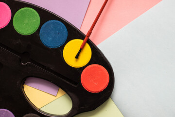 multicolored paints on with brushes on cardboard