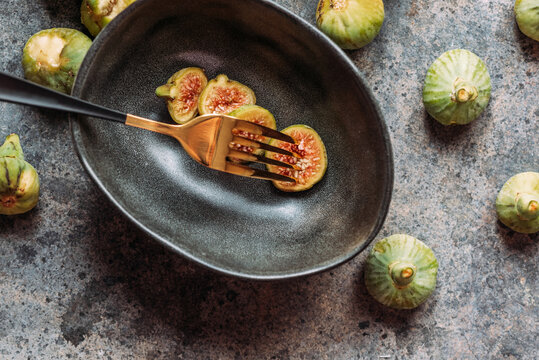 Green fig slices in modern black bowl on the table with grunge texture. minimal concept food. Also known as ripe white figs