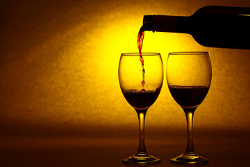 Silhouette of a red wine bottle and wine glasses with a yellow sunlight sunset type light burst