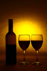 Silhouette of a red wine bottle and wine glasses with a yellow sunlight sunset type light burst