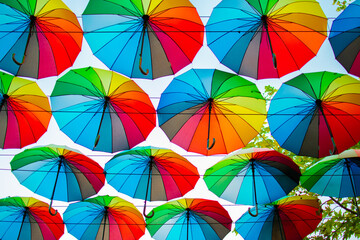 Multicolored rainbow umbrellas against the sky, summer street decor