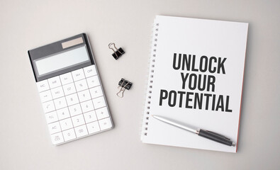 The word Unlock Your Potential is written on a white background next to a pen ,calculator and reports. Business concept