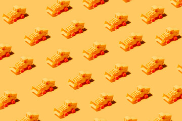 High angle collection of similar tractor toys symmetrical arranged on yellow surface as abstract background
