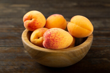 Fresh apricots in a wooden plate.