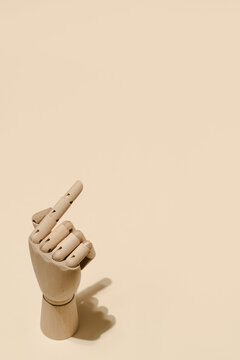 High angle of wooden hand with index finger pointing up on beige background in studio