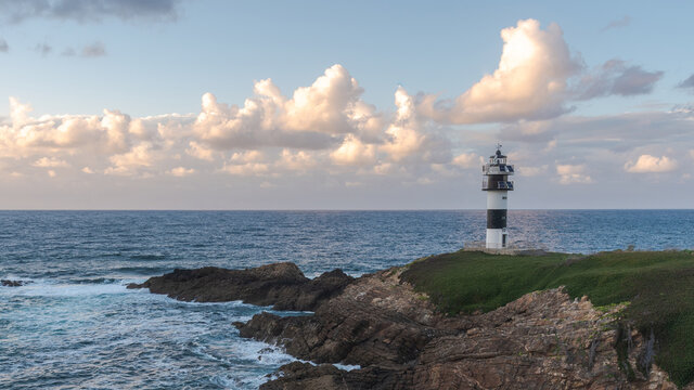 Picturesque scenery of grassy shore with lighthouse placed near blue ocean in Faro Illa Pancha in Galicia in Spain in daytime