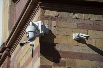 closeup of white security cameras of security on stoned wall by sunny day
