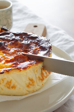 Cropped unrecognizable person slicing delicious baked cheesecake with knife served on a plate