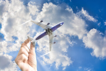 Toy plane in the blue sky hold by hand suggesting abstract concept of free flying again