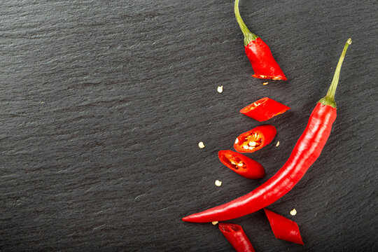 Red chili pepper on a black slate board.