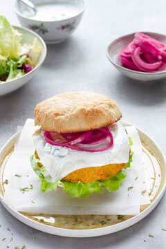 Appetizing homemade veggie curry and mango chickpea burger with fresh lettuce and picked red onion and soy cheese served with yogurt sauce