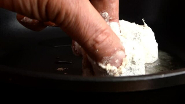 Cooking white sea fish hake, cut into pieces in frying pan. Baked hake or pollock with golden crust preparation on domestic kitchen. Fried fish recipe. Selective focus. Close-up.