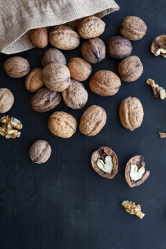 From above bag with whole and halved walnuts with dry nutshells and heart shaped center on table