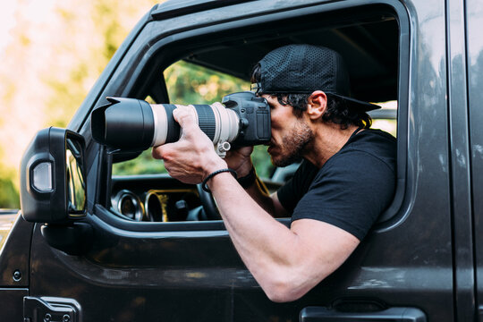 Side view of an adventurous photographer taking photos from inside his off-road car