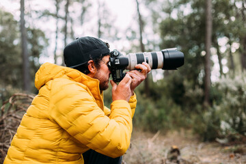 Side view of an adventurous photographer taking photos in the mountain with blur background