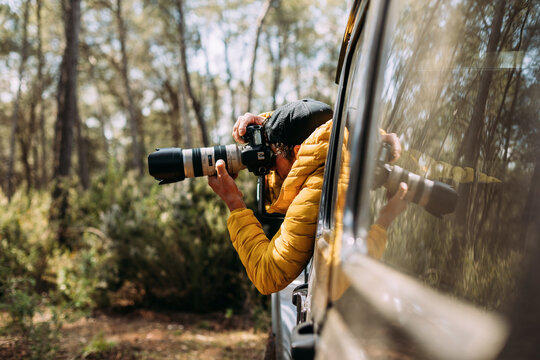 Side view of an adventurous photographer taking photos from inside his off-road car