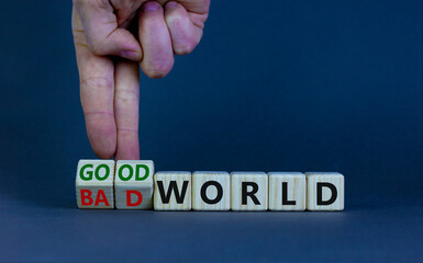 Good or bad world symbol. Businessman turns wooden cubes and changes words 'bad world' to 'good world'. Beautiful grey table, grey background, copy space. Business and good or bad world concept.