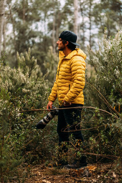 Side view of a photographer in a cap and yellow jacket on the mountain looking away
