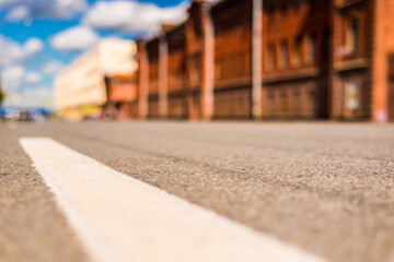 Summer in the city, the empty street with the building of red brick. Close up view from the level of the dividing line