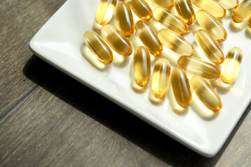 Cod liver oil capsules. Bright yellow pills on a plate. 