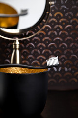 A black toothbrush is reflected in the gold mirror.