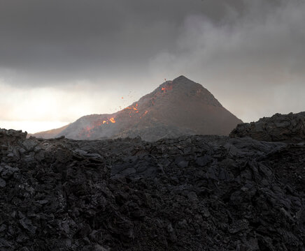 Side view of magma sparks out of the volcano hole and run like rivers of lava over the ground in Iceland