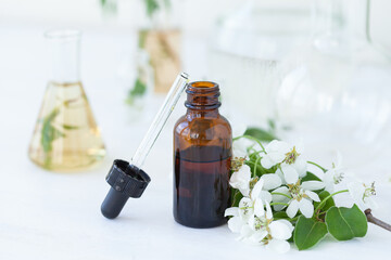 Concept of laboratory drug research for beauty products. Natural organic ingredients, pure herbal and flower extract, medical ingredients for cosmetics in glassware. Close up, white background
