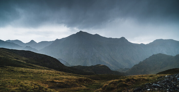 Landscape of Aran valley with majestic green hills and dark gray gloomy sky above