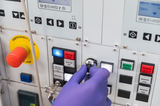 Crop unrecognizable professional male laboratory assistant in white robe and latex gloves pressing buttons on modern equipment