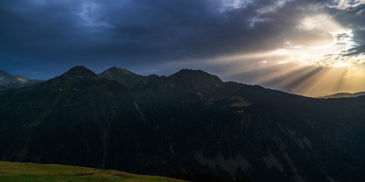 Spectacular landscape of Pyrenees range of Aran valley with sunbeams shining through dense stormy clouds