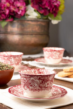 Ornamental ceramic cups served on table with flowers for teatime in cozy room at home