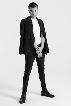 Serious male model in fashionable suit standing on white background in studio and looking away