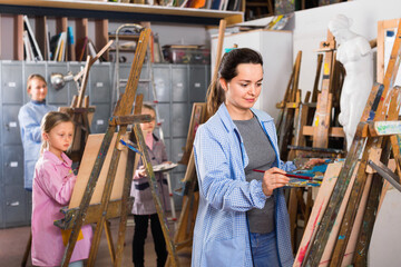 Skillful cheerful positive students working patiently during painting class at art studio