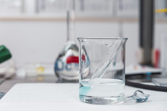 Test tube with blue chemical fluid placed in cold water in glass jar in modern equipped laboratory