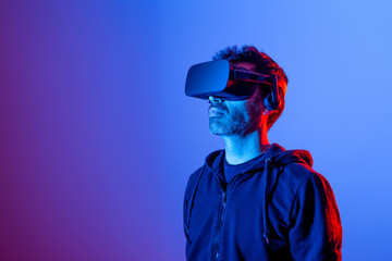 Unrecognizable bearded male in headset exploring virtual reality in neon light