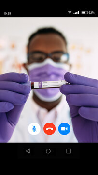 Anonymous African American professional doctor in medical gloves demonstrating vaccine online in video call in soft focus