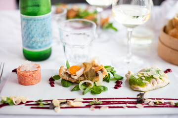 Fish tartar and other freshly cooked fish dinner with white wine. Shallod depth of field with selective focus only on fish