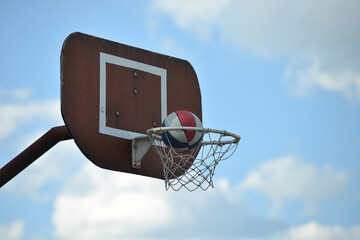 Basketball going in net  on blue sky outdoors