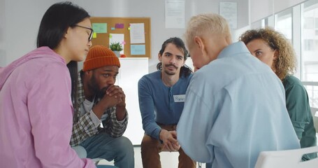 Diverse people supporting senior crying woman at therapy session - Powered by Adobe