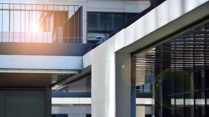 Fototapeta premium Modern architecture with sun ray. Glass and steel facade on a bright sunny day with sunbeams on the blue sky. Economy, finances, business activity concept.