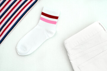 stylish flat lay: white jeans, white socks with red stripes and a striped top