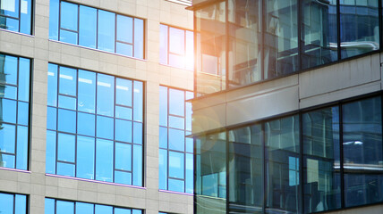 Obraz premium Modern architecture with sun ray. Glass and steel facade on a bright sunny day with sunbeams on the blue sky. Economy, finances, business activity concept.