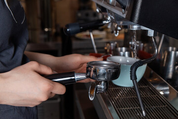 barista prepares and pours coffee into a mug on the coffee machine, close-up, hands of a woman, blurred background