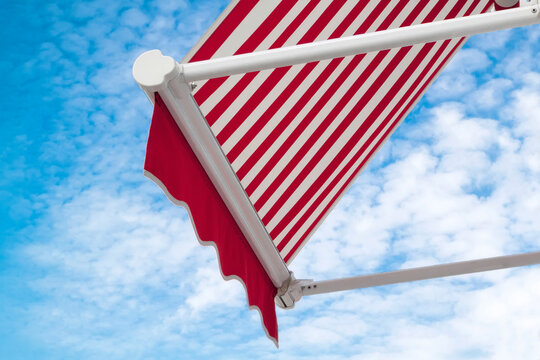 red and white striped cafe canopy awning against blue cloudy sky