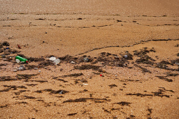 Poured trash on the beach - empty used dirty plastic bottles, packages and other household rubbish.