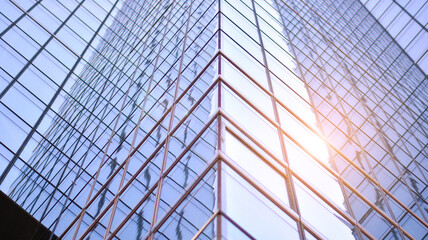 Fototapeta premium Modern architecture with sun ray. Glass and steel facade on a bright sunny day with sunbeams on the blue sky. Economy, finances, business activity concept.
