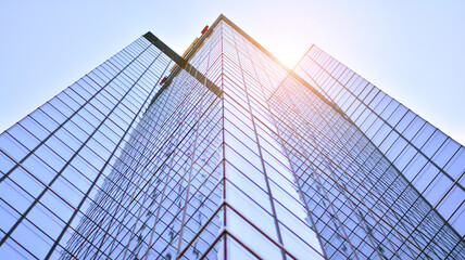 Modern architecture with sun ray. Glass and steel facade on a bright sunny day with sunbeams on the blue sky. Economy, finances, business activity concept.